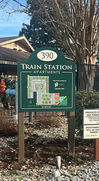 An exterior post and panel sign for Train Station Apartments. It is a wayfinding sign that shows the layout of the apartment complex for people entering the facility.